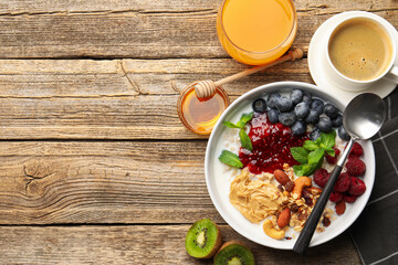 Naklejka premium Healthy breakfast. Oatmeal with nuts, berries, yoghurt, coffee and orange juice on wooden table, flat lay. Space for text