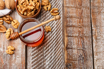 Honey in jar, walnuts and dipper on wooden table, flat lay. Space for text