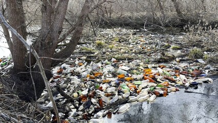 Dirty river is polluted with many plastic bottles. A lot of trash is dumped in open and freely available places at nature. Global environmental pollution problem. Concept of ecological disaster