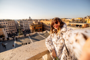 Smiling woman enjoying New Year 2025 celebration on a terrace overlooking Rome near the Spanish Steps. Festive atmosphere, winter tourism, holiday travel, freedom, joy, and European city lifestyle