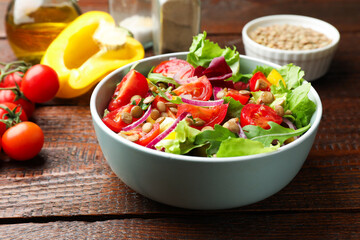 Delicious lentil salad and ingredients on wooden table, closeup