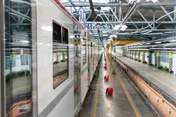 A metro train is at a station platform while passengers wait to board. The environment shows a busy transportation hub in an urban setting