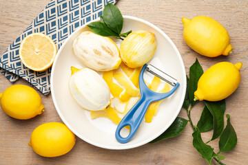 Fresh lemons with zest, peeler and leaves on wooden table, flat lay