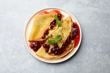 Tasty crepes with cherries, jam and mint on light table, top view