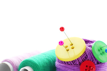 Ball of bright knitting yarn with buttons, spools of thread and pins on white background