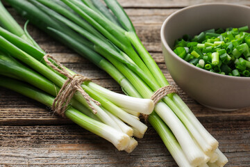 Fresh ripe green onions on wooden table, closeup