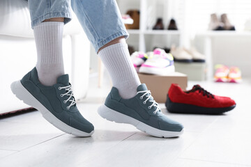 Woman trying on sneakers in shoe store, closeup
