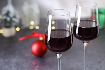 Glasses of red wine and Christmas decor on grey table, closeup. Space for text