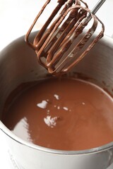 Chocolate dough dripping from mixer into bowl, closeup
