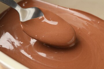 Taking liquid chocolate dough with spoon from baking dish, closeup