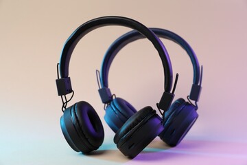 Stylish headphones on color gradient background, closeup view