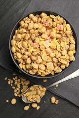 Tasty granola with dried fruits in bowl on black table, flat lay
