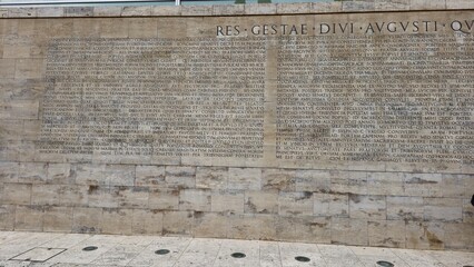 Rome, Italy - 12 January 2025. The Res Gestae text is carved in Latin on a stone wall near the Ara Pacis, detailing Augustus&rsquo; accomplishments in bold capital letters.