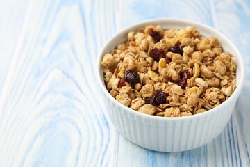 Tasty granola with dried fruits in light blue wooden table, closeup. Space for text