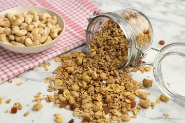 Tasty granola in glass jar on white marble table, closeup