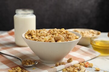Tasty granola with dried fruits and nuts in bowl and milk on white marble table, closeup