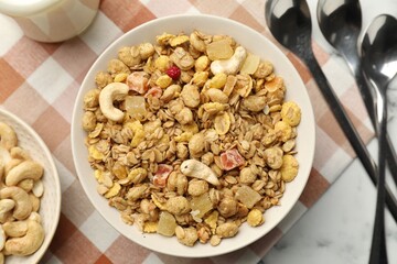 Tasty granola with dried fruits and nuts in bowl on white marble table, flat lay