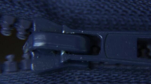A close-up of the zipper being unzipped in motion. hardware material: metal zipper macro.