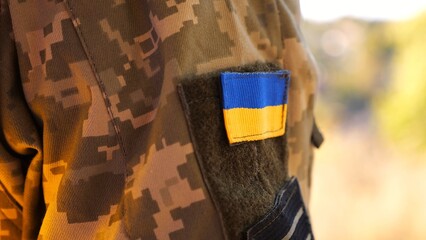 Close up of military blue-yellow chevron on shoulder of soldier at countryside. This emblem embodies the unbreakable spirit and pride of the ukrainian people. Concept of invasion resistance