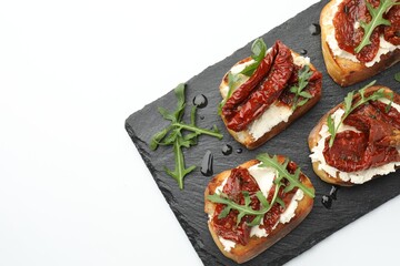 Delicious bruschettas with cream cheese, sun-dried tomatoes and arugula on white table, top view. Space for text
