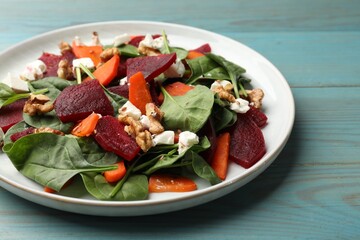 Delicious salad with beetroot, spinach, cheese, walnuts and carrot on blue wooden table, closeup