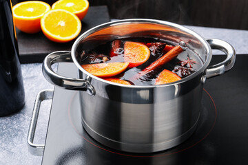 Tasty mulled wine cooking in pot on stove, closeup