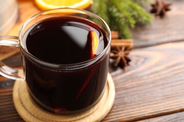 Tasty mulled wine in glass on wooden table, closeup. Space for text