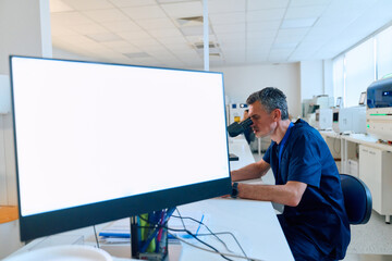 Scientist examining samples under microscope in modern laboratory setting during daytime work hours