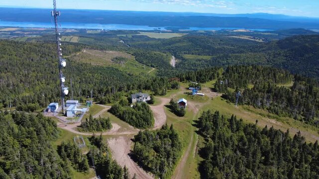 The summit of the mountain in Val D'Irene Regional Park, with its communications antenna tower offering a breathtaking view of Lake Matapedia in the distance. Quebec, Canada, 2025.