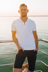 Confident Man In White Polo At Waterfront Sunset