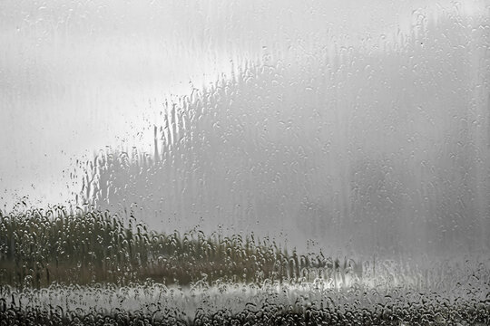 Blick durch eine regennasse Fensterscheibe &ndash; Starkregen prasselt gegen das Glas