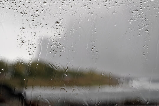 Blick durch eine regennasse Fensterscheibe &ndash; Regenwasser l&auml;uft am Glas herunter