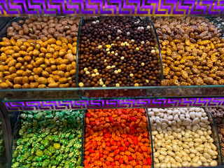 Colorful glazed nuts arranged in Istanbul bazaar. Abundance, choice freedom, visual rhythm, and retail temptation expressed through confectionery variety.