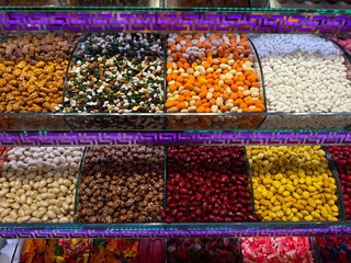 Wide confectionery showcase filled with glazed nuts and candies in symmetrical rows in Istanbul bazaar. Visual order, consumer attraction, playful color balance, and sensory overload within modern