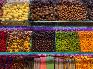 Close view of glazed nuts separated by glass dividers in a confectionery counter in Istanbul bazaar. Texture emphasis, color contrast, indulgent choice, and tactile appeal within premium snack