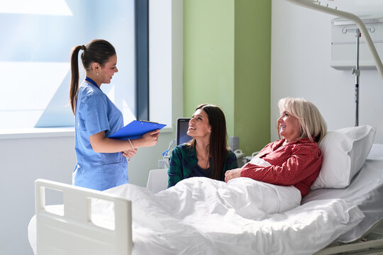 Nurse discussing care plan with patients in hospital room during afternoon hours