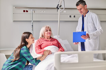 Obraz premium Caring nurse speaks with patient and family in a hospital room during consultation about health