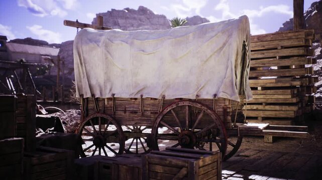 A rustic wooden wagon, covered with a white cloth, is positioned among crates in an outdoor setting. The background features rocky cliffs and scattered vegetation, indicating a remote location.