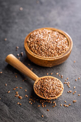Linseed or flaxseed. Healthy flax seed on wooden spoon on black table.