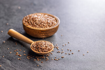 Linseed or flaxseed. Healthy flax seed on wooden spoon on black table.