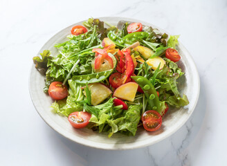 Fresh mixed green salad with cherry tomatoes on white plate