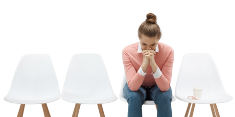 Young woman sitting in the line or queue, looking stressed, putting hands together as if she is praying to overcome depression