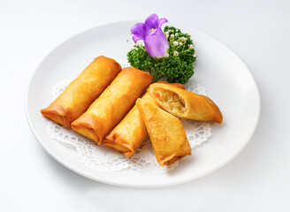 Delicious spring rolls on a white plate with purple flower garnish