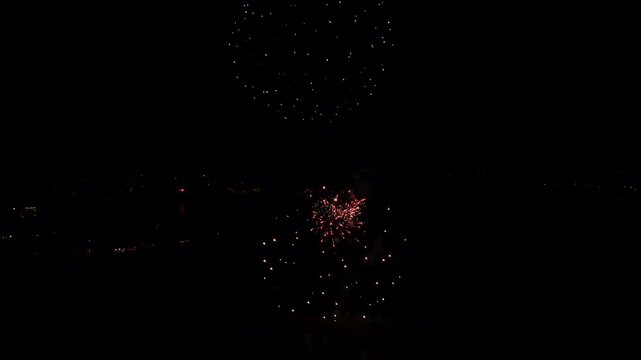 Drone view of the fireworks bursting over the ocean at night in Algarve, Portugal