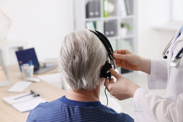 Hearing test. Doctor adjusting patient's audiometric headphones in clinic, closeup © New Africa