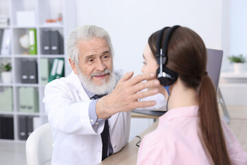Hearing test. Doctor adjusting patient's audiometric headphones in clinic