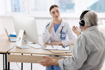 Fototapeta premium Patient with audiometric headphones undergoing hearing test in clinic, selective focus