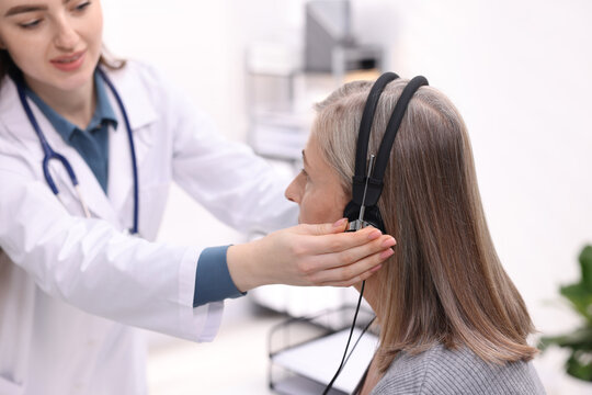Hearing test. Doctor adjusting patient's audiometric headphones in clinic, selective focus