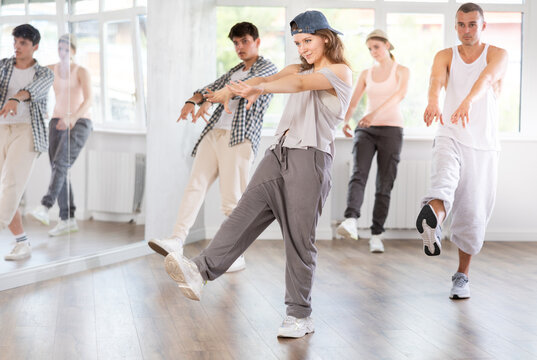 Active young girl practicing kicking move of hip-hop in training hall during dancing classes