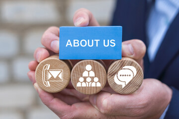 About us and contact us business web concept. Business person holding blocks with icons sees the inscription ABOUT US.